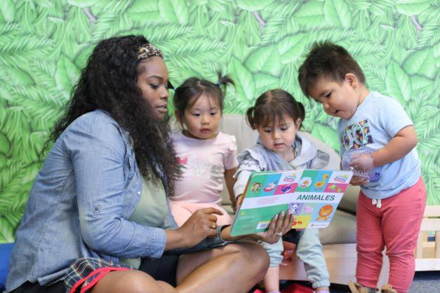 teacher with three infants reading book